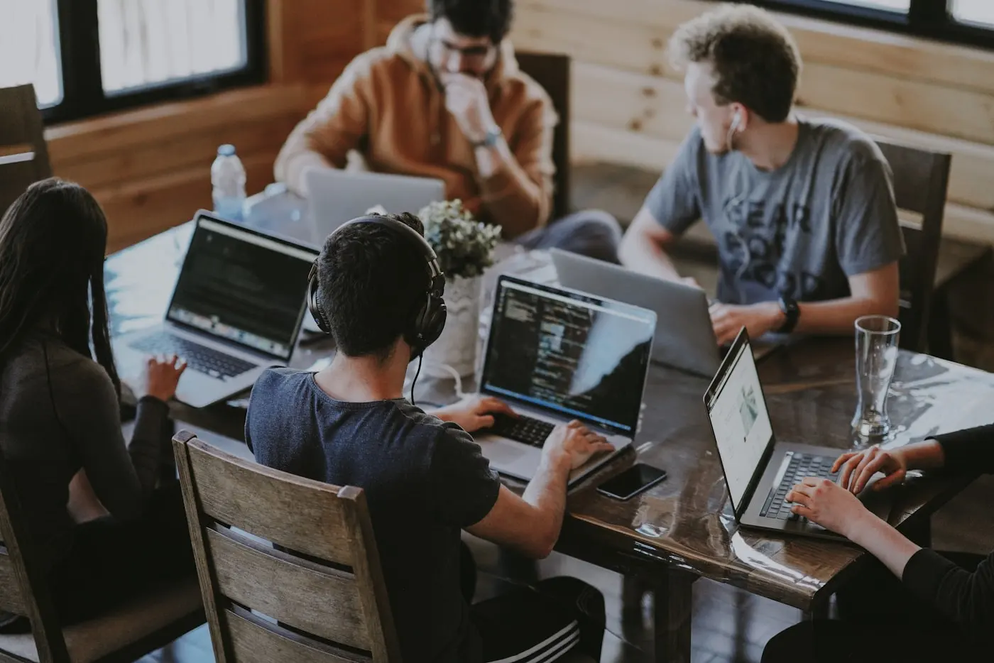 Equipo de trabajo joven reunido alrededor de una mesa con portátiles