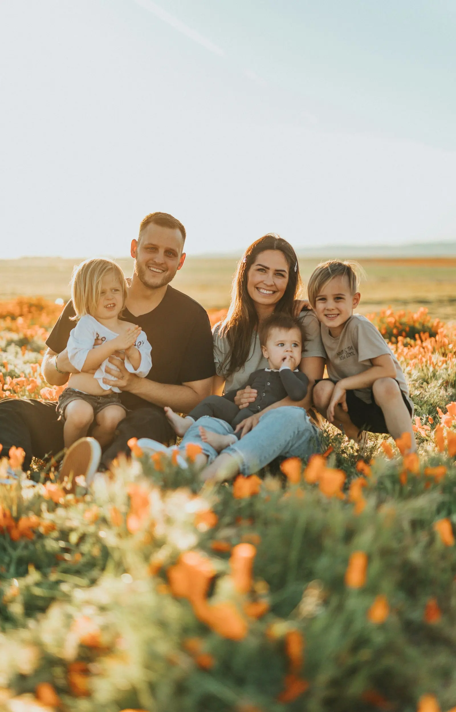 Familia joven sentada en un campo de flores al atardecer